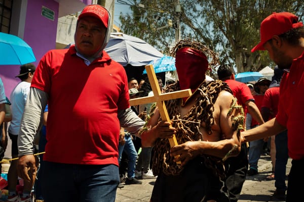 Mexican man in chains walking through streets of Atlixco as a part of local semana santa tradition called los engrillados.