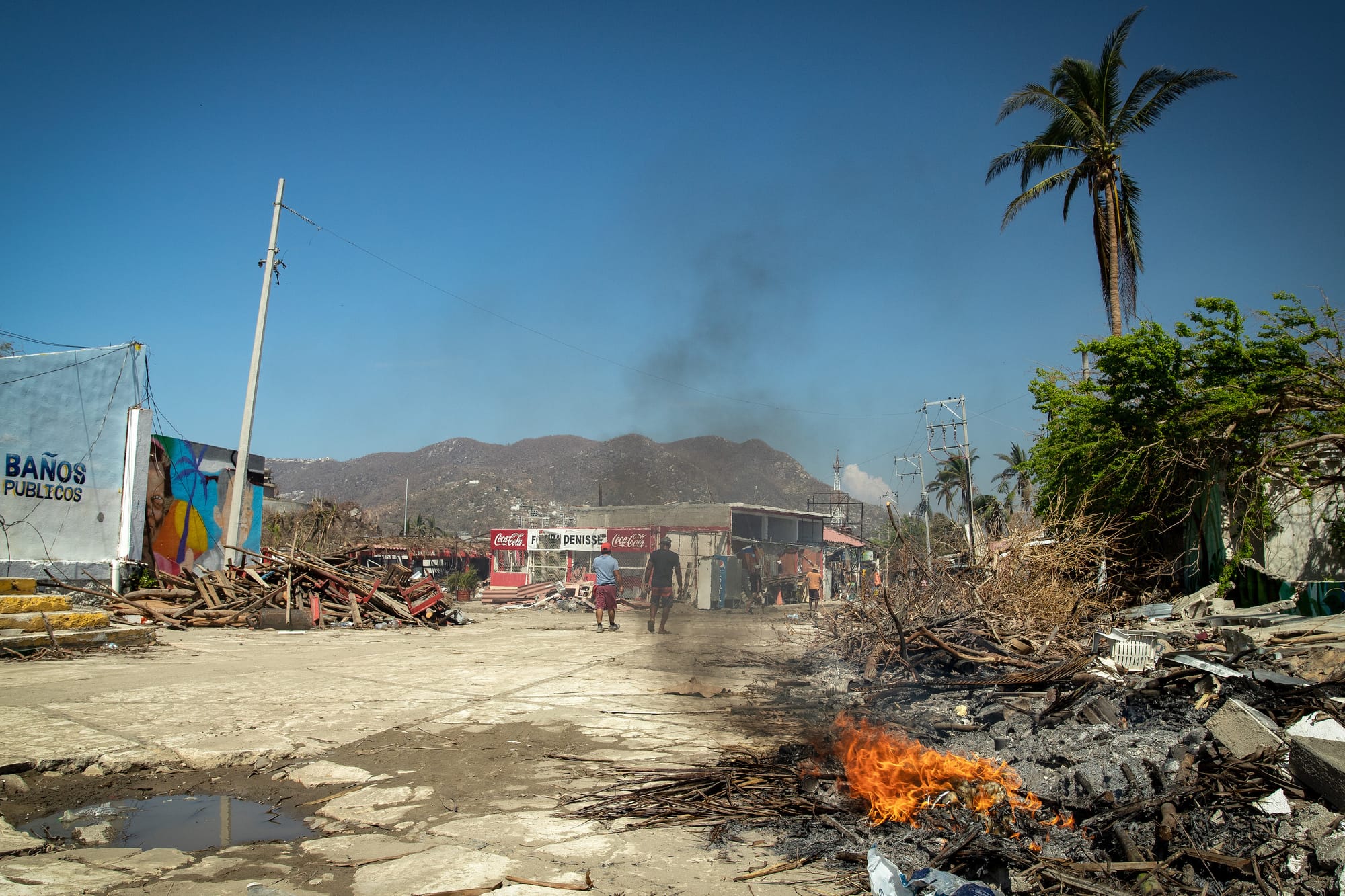 people in acapulco are burning waste as the debris and waste stays in the streets