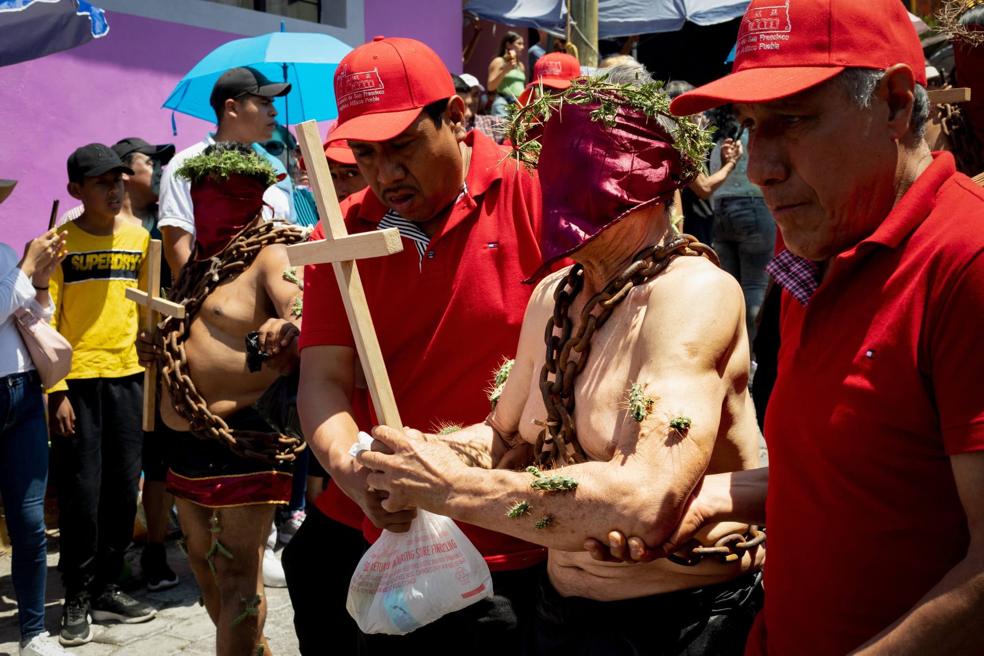 Mexican man in chains, with cross and thorns crown walking through streets of Atlixco, Puebla as a part of local semana santa tradition called los engrillados.