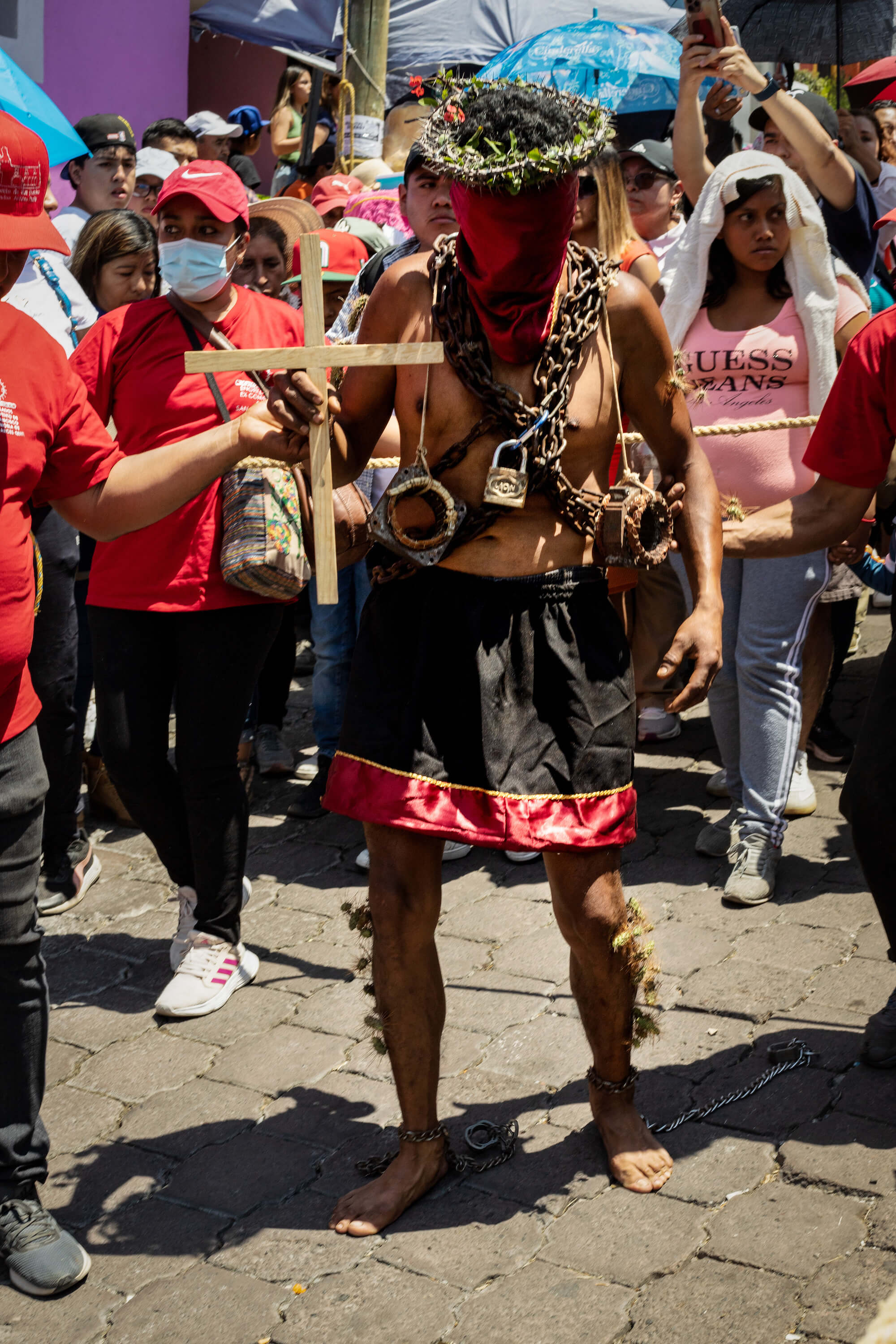 Mexican man in chains, with cross and thorns crown walking through streets of Atlixco, Puebla as a part of local semana santa tradition called los engrillados.